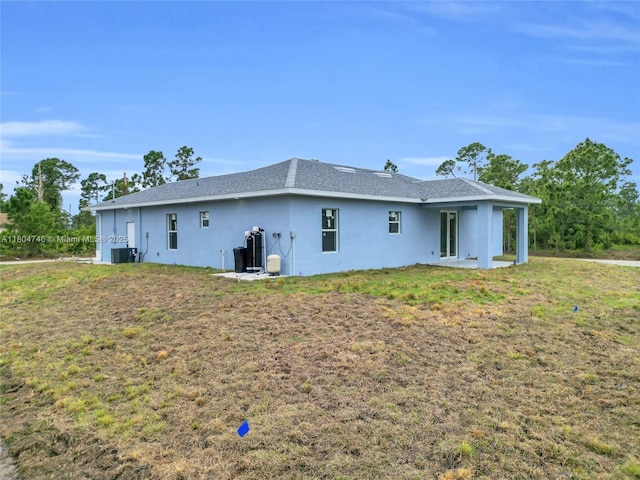 935 Elgin St, Lehigh Acres, FL 33974 - rear view of house featuring stucco siding, central AC, and a lawn