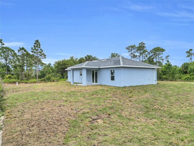 935 Elgin St, Lehigh Acres, FL 33974 - rear view of property featuring a lawn, stucco siding, and a shingled roof