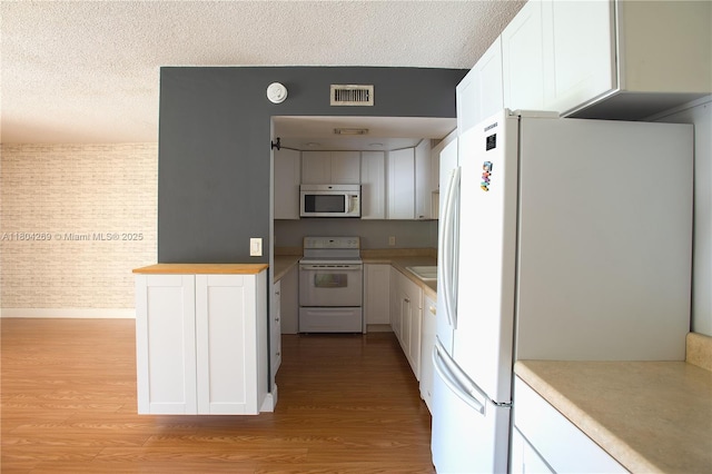 4200 Crystal Lake Dr Unit 204, Deerfield Beach, FL 33064 - kitchen with white appliances, light wood-style floors, a textured ceiling, and white cabinetry