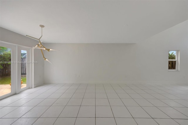 empty room featuring plenty of natural light, light tile patterned flooring, and baseboards