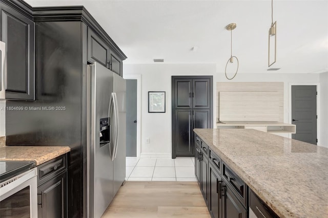 kitchen featuring light stone countertops, decorative light fixtures, dark cabinets, light wood-style flooring, and stainless steel refrigerator with ice dispenser
