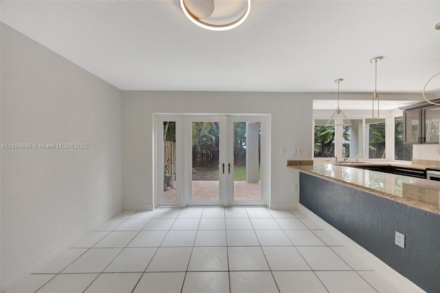 unfurnished dining area with light tile patterned flooring, french doors, baseboards, and a sink