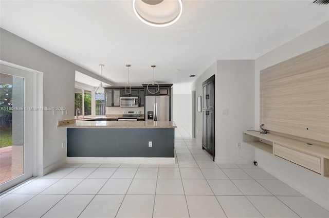 kitchen with stainless steel appliances, a peninsula, decorative light fixtures, a sink, and light stone counters