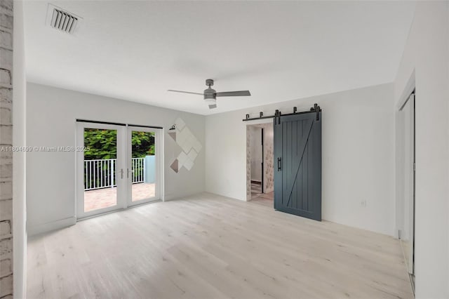 unfurnished room featuring wood finished floors, ceiling fan, and a barn door