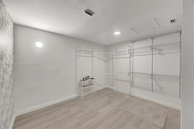 spacious closet with attic access and light wood-style floors