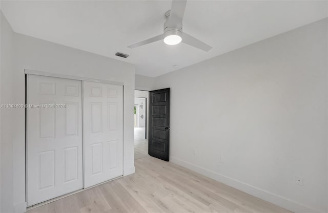 unfurnished bedroom with light wood-type flooring, baseboards, a closet, and a ceiling fan