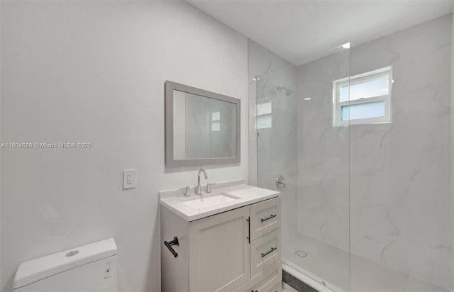 bathroom featuring a marble finish shower, toilet, and vanity
