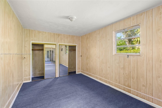 1242 Sevilla Ave, Coral Gables, FL 33134 - unfurnished bedroom featuring two closets, carpet, wood walls, and baseboards