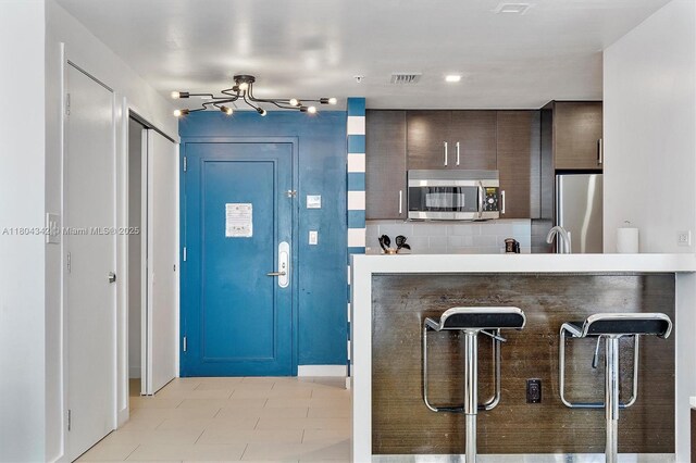 17315 Collins Ave Unit 1008, Sunny Isles Beach, FL 33160 - kitchen featuring stainless steel appliances, a breakfast bar, dark brown cabinets, and a peninsula