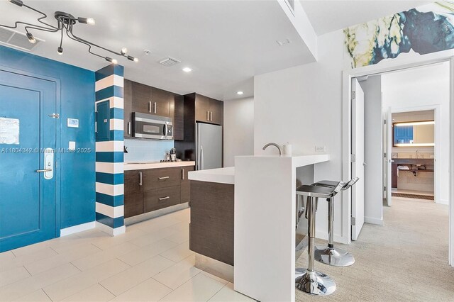 17315 Collins Ave Unit 1008, Sunny Isles Beach, FL 33160 - kitchen featuring appliances with stainless steel finishes, dark brown cabinets, light countertops, a breakfast bar, and a peninsula