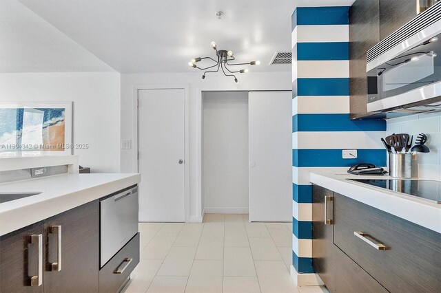 17315 Collins Ave Unit 1008, Sunny Isles Beach, FL 33160 - kitchen featuring stainless steel appliances, light countertops, a chandelier, light tile patterned floors, and dark brown cabinets