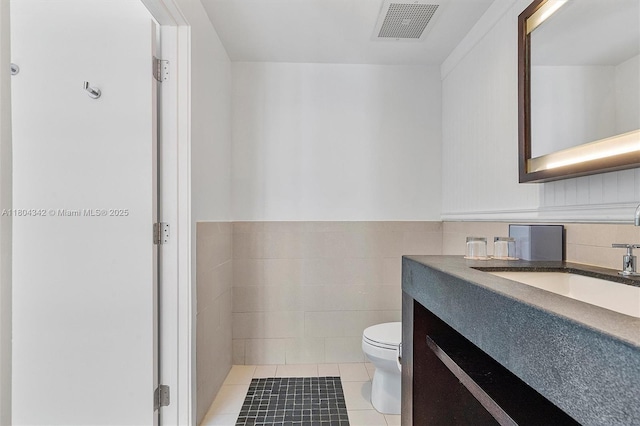 17315 Collins Ave Unit 1008, Sunny Isles Beach, FL 33160 - bathroom featuring toilet, tile patterned flooring, vanity, tile walls, and wainscoting