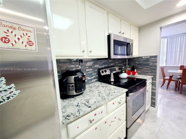 16565 NE 26th Ave Unit 2B, North Miami Beach, FL 33160 - kitchen with stainless steel appliances, decorative backsplash, white cabinets, and light stone countertops