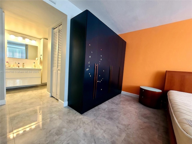 16565 NE 26th Ave Unit 2B, North Miami Beach, FL 33160 - bedroom with marble look tile flooring, baseboards, ensuite bathroom, and a closet