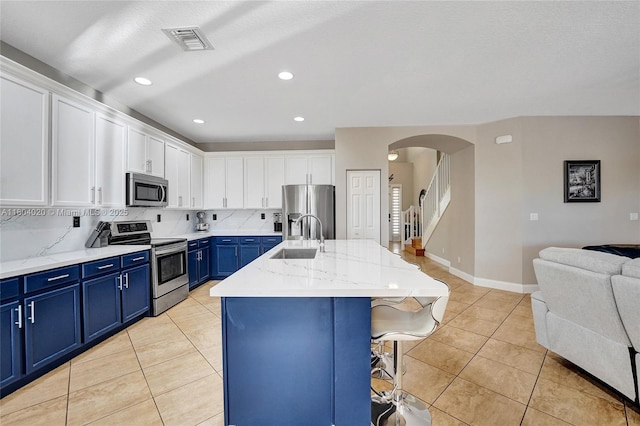 4470 E Seneca Ave, Weston, FL 33332 - kitchen with appliances with stainless steel finishes, blue cabinets, open floor plan, arched walkways, and white cabinetry