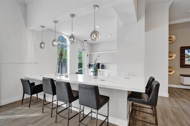 4470 E Seneca Ave, Weston, FL 33332 - kitchen featuring a peninsula, white cabinets, stainless steel microwave, a kitchen bar, and light countertops