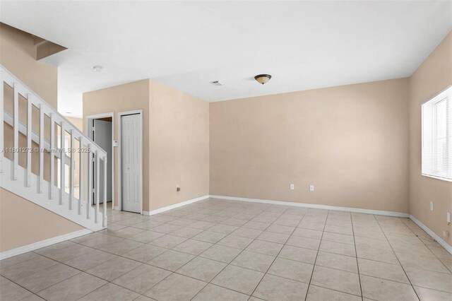 2946 SE 15th Ter, Homestead, FL 33035 - empty room with light tile patterned floors, stairway, and baseboards
