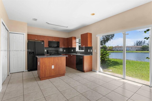 2946 SE 15th Ter, Homestead, FL 33035 - kitchen featuring black appliances, a kitchen island, tasteful backsplash, light tile patterned flooring, and a water view