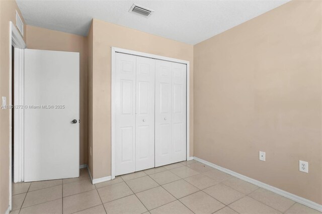 2946 SE 15th Ter, Homestead, FL 33035 - unfurnished bedroom with baseboards, a closet, and light tile patterned floors