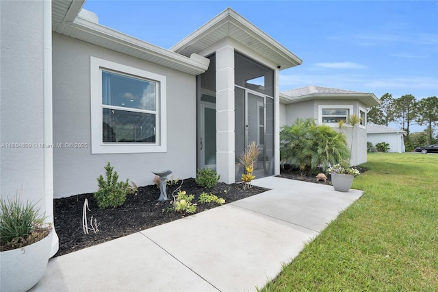 1020 Rush Ave, Lehigh Acres, FL 33972 - view of exterior entry featuring stucco siding and a lawn