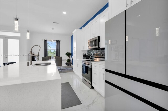 1020 Rush Ave, Lehigh Acres, FL 33972 - kitchen featuring appliances with stainless steel finishes, a sink, light marble finish flooring, decorative backsplash, and pendant lighting