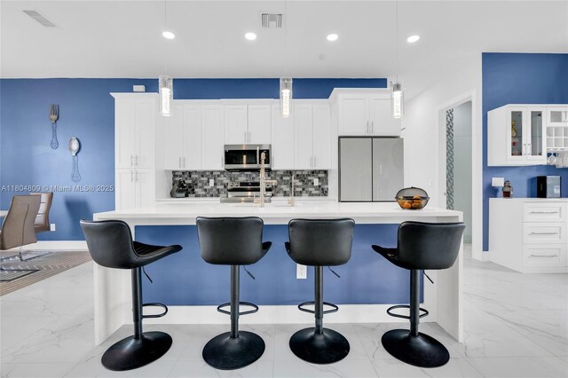 1020 Rush Ave, Lehigh Acres, FL 33972 - kitchen with appliances with stainless steel finishes, backsplash, a large island with sink, white cabinetry, and light countertops