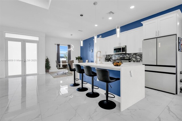 1020 Rush Ave, Lehigh Acres, FL 33972 - kitchen with stainless steel appliances, light marble finish flooring, an island with sink, decorative backsplash, and french doors