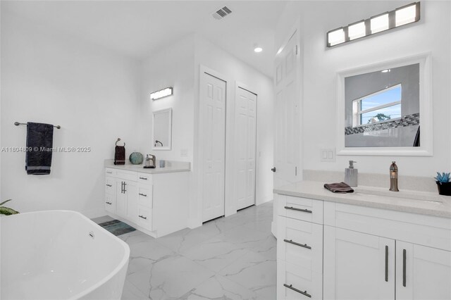1020 Rush Ave, Lehigh Acres, FL 33972 - full bathroom with marble finish flooring, a soaking tub, two vanities, recessed lighting, and baseboards