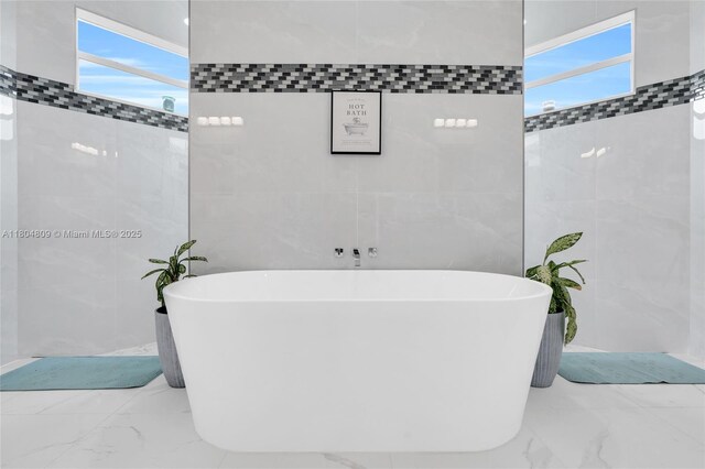 1020 Rush Ave, Lehigh Acres, FL 33972 - bathroom featuring tile walls, marble tiled floors, and a freestanding tub
