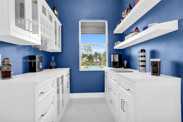 1020 Rush Ave, Lehigh Acres, FL 33972 - kitchen featuring light marble finish floors, baseboards, glass insert cabinets, open shelves, and white cabinetry