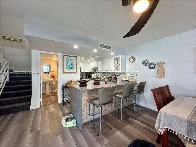 14367 SW 96th Ln, Miami, FL 33186 - kitchen with dark wood-type flooring, a peninsula, white cabinets, a breakfast bar, and recessed lighting