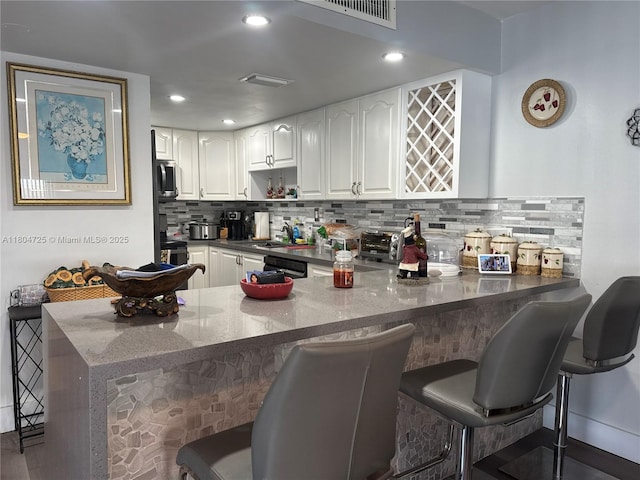 14367 SW 96th Ln, Miami, FL 33186 - kitchen with a peninsula, a breakfast bar, dark stone counters, white cabinetry, and decorative backsplash