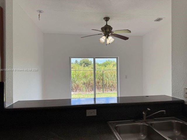 kitchen with a sink, ceiling fan, and dark countertops