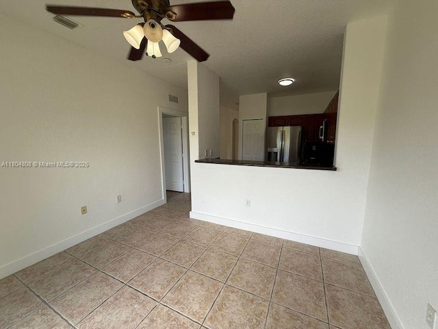empty room with light tile patterned floors, a ceiling fan, and baseboards