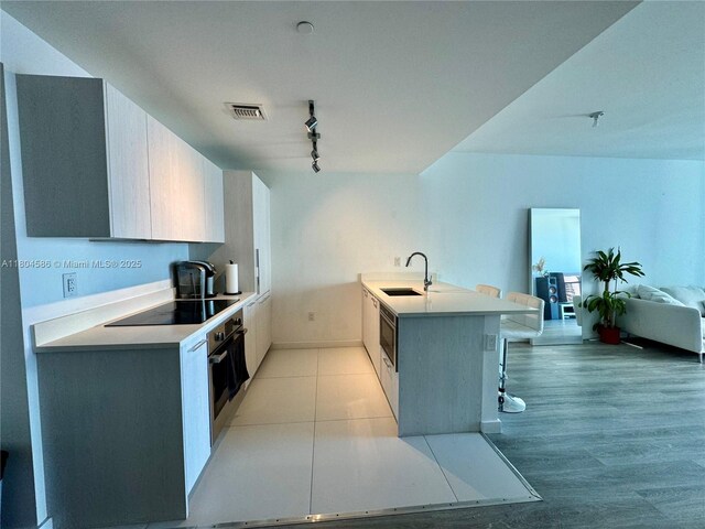 501 NE 31st St Unit 2903, Miami, FL 33137 - kitchen featuring black electric cooktop, a sink, a kitchen breakfast bar, track lighting, and a peninsula