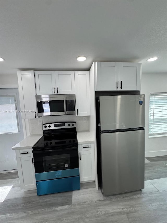 1794 NW 74th Ter, Miami, FL 33147 - kitchen featuring appliances with stainless steel finishes, light wood-type flooring, white cabinets, baseboards, and recessed lighting