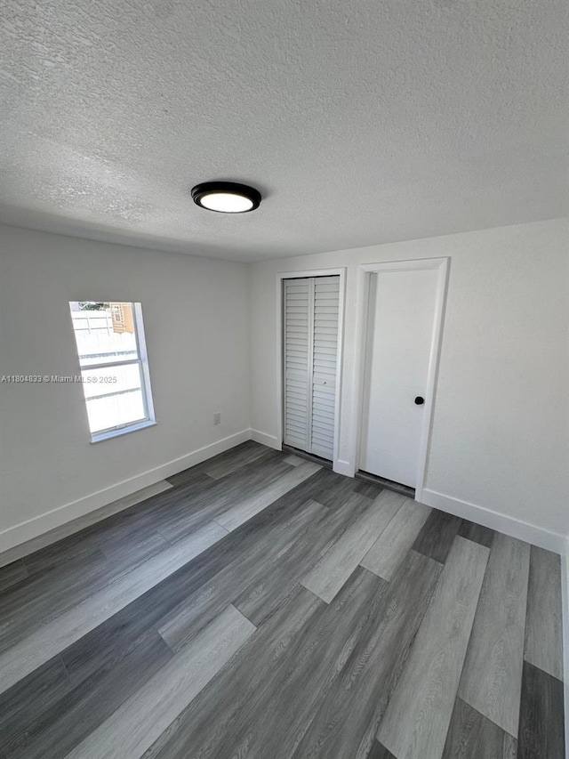 1794 NW 74th Ter, Miami, FL 33147 - unfurnished bedroom featuring baseboards, dark wood-style flooring, a textured ceiling, and a closet