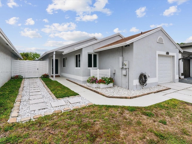 rear view of property with a garage, stucco siding, and driveway