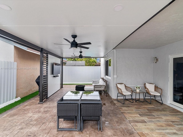 view of patio with fence, a ceiling fan, and outdoor dining area