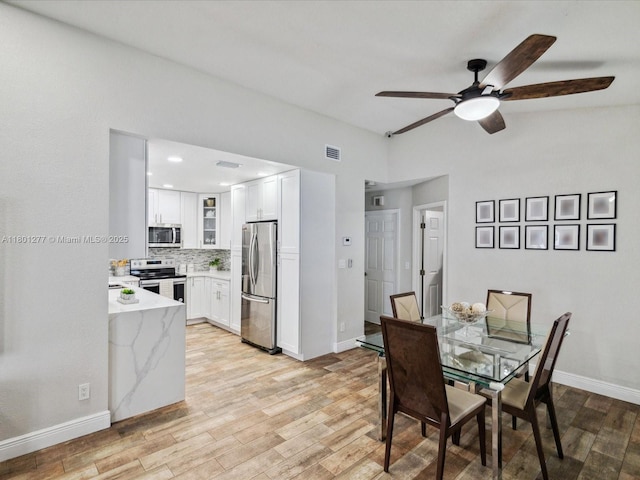 dining space with light wood-type flooring, ceiling fan, and baseboards