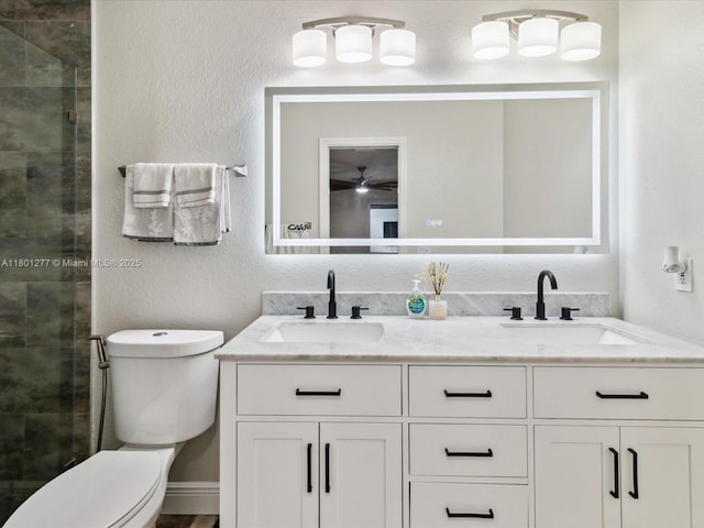 full bathroom featuring double vanity, a stall shower, toilet, and a textured wall