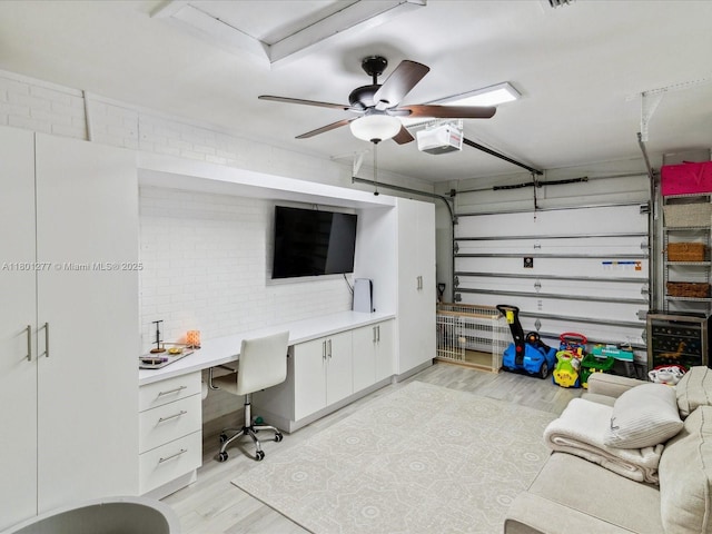 garage with a desk, a garage door opener, and a ceiling fan