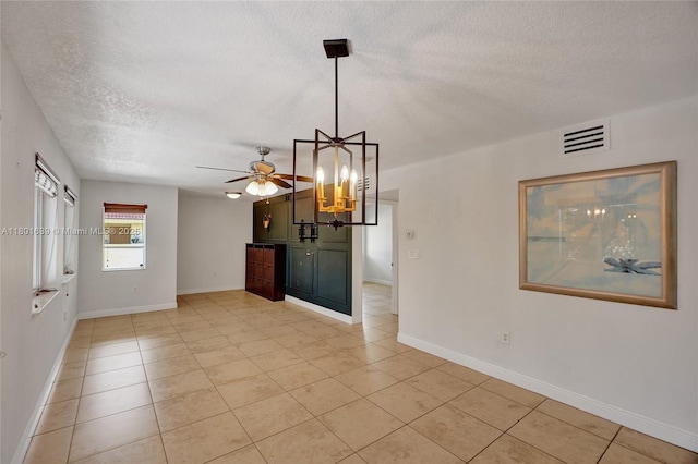 6235 SW 47th Mnr Unit 204, Davie, FL 33314 - unfurnished living room with a textured ceiling, light tile patterned floors, baseboards, a ceiling fan, and a chandelier