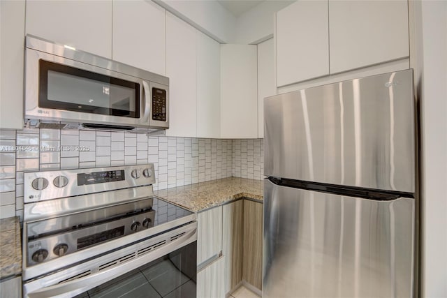 7330 NW 114th Ave Unit 304-5, Doral, FL 33178 - kitchen with appliances with stainless steel finishes, white cabinetry, light stone counters, tasteful backsplash, and modern cabinets