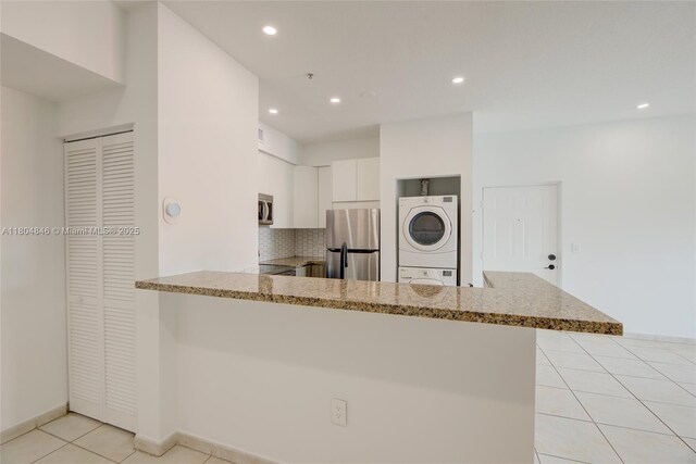 7330 NW 114th Ave Unit 304-5, Doral, FL 33178 - kitchen with stacked washing machine and dryer, stainless steel appliances, a peninsula, light tile patterned flooring, and white cabinets