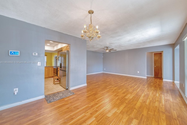 7717 Coral Blvd, Miramar, FL 33023 - empty room with light wood-style flooring, ceiling fan, a chandelier, baseboards, and a textured ceiling