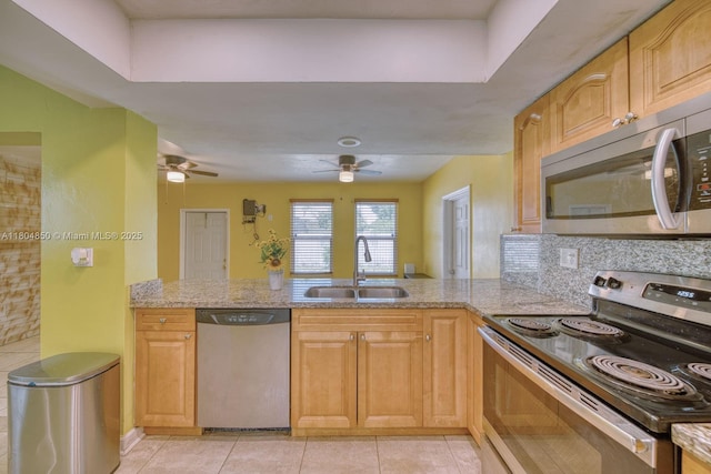 7717 Coral Blvd, Miramar, FL 33023 - kitchen featuring stainless steel appliances, a sink, a peninsula, a ceiling fan, and light stone countertops
