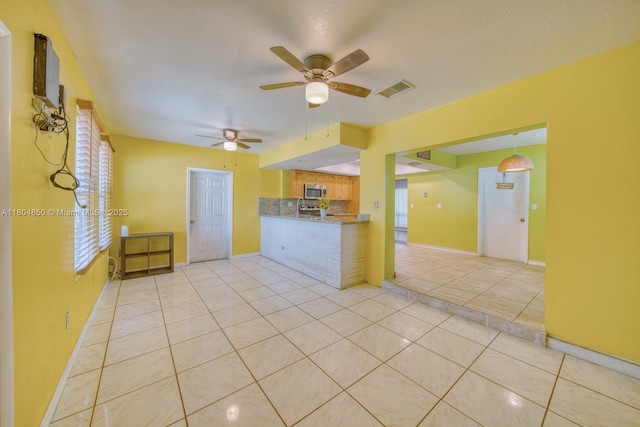7717 Coral Blvd, Miramar, FL 33023 - kitchen with light tile patterned floors, stainless steel microwave, a ceiling fan, tasteful backsplash, and baseboards