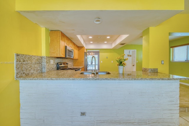 7717 Coral Blvd, Miramar, FL 33023 - kitchen featuring a sink, appliances with stainless steel finishes, a peninsula, light stone counters, and tasteful backsplash