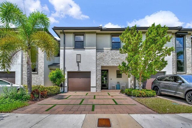 15678 NW 91st Ct, Miami Lakes, FL 33018 - view of property with stone siding, stucco siding, an attached garage, and driveway